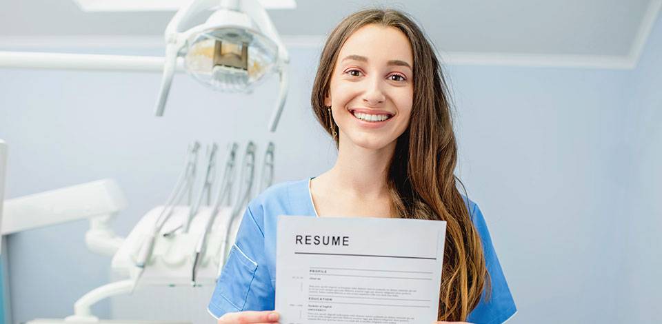 Female in scrubs holding document titled Resume
