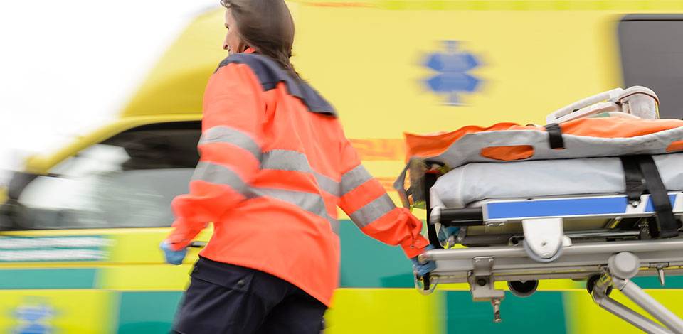 Ambulance worker pulling bed to an ambulance