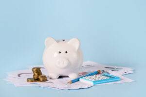 Piggy bank with savings, calculator and documents on color backg